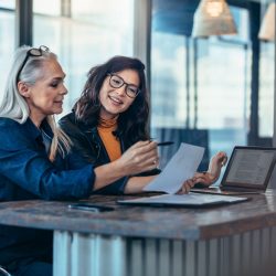 Two women analyzing documents at office